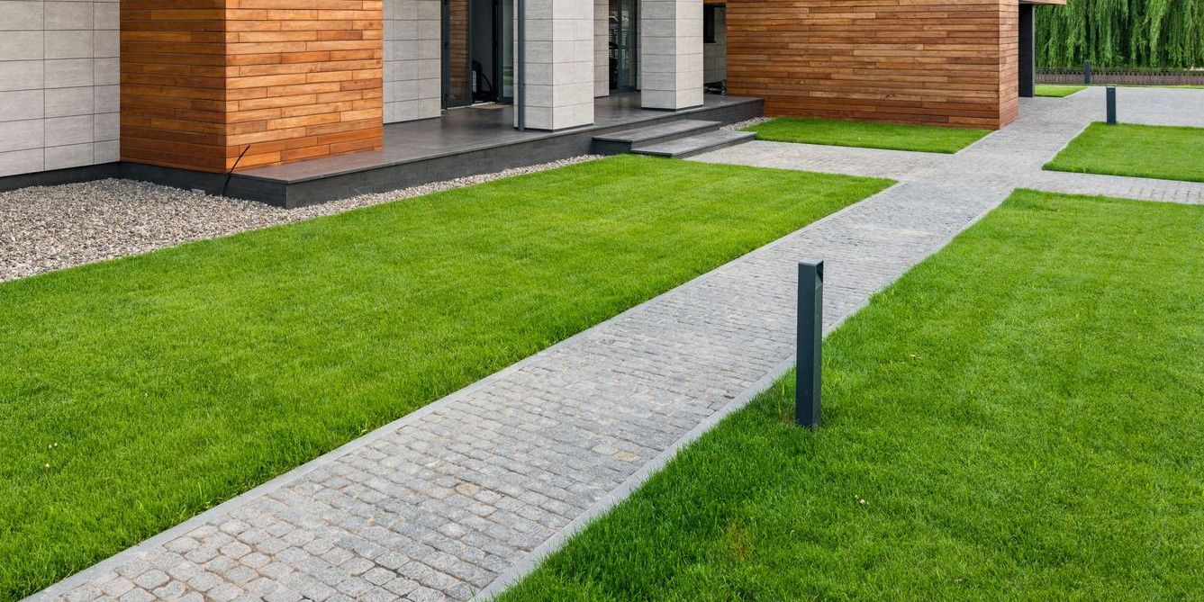 Exterior of contemporary residential house with green lawn and paths in sunny day